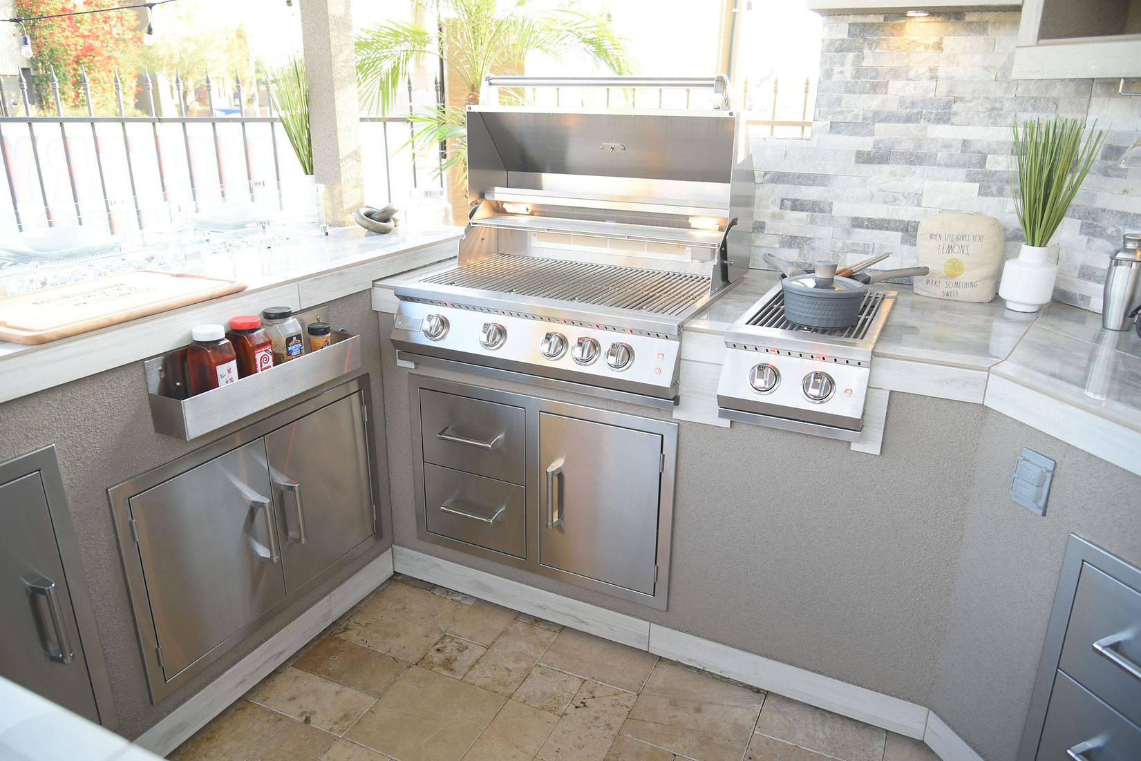 Outdoor kitchen with stainless steel appliances and gray cabinets.