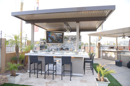Outdoor kitchen with bar stools and a TV screen on a patio