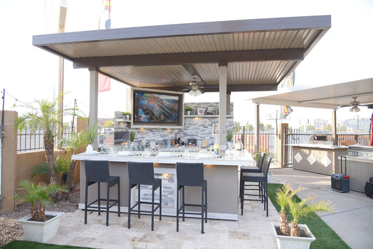 Outdoor kitchen with bar stools and a TV screen on a patio