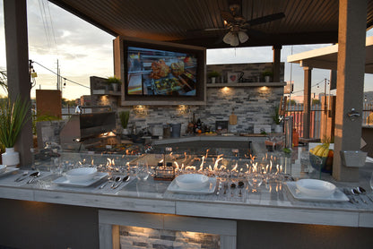 Bermuda custom outdoor kitchen featuring a built-in fire table, premium grill, outdoor television, beverage station, and covered entertaining space