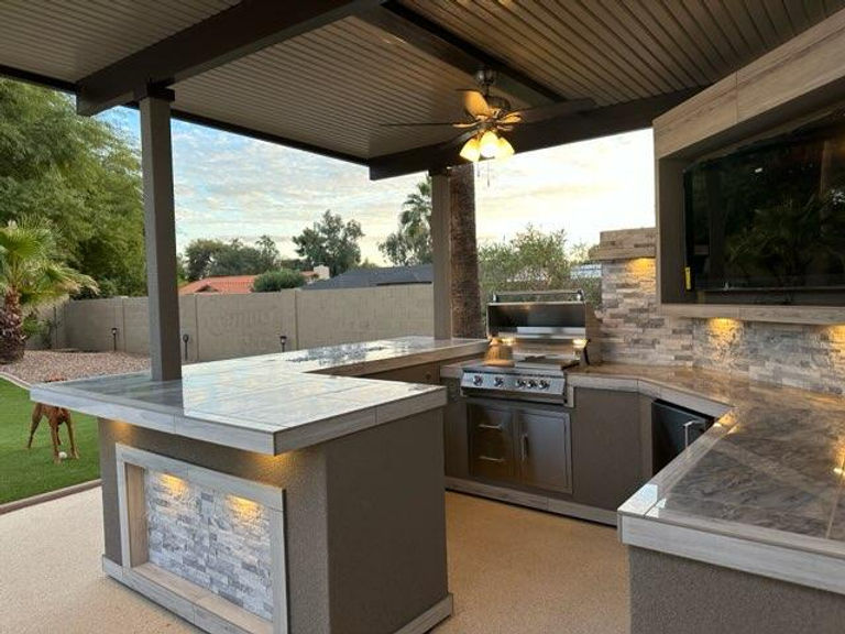 Modern outdoor kitchen with stone countertops and ceiling fans