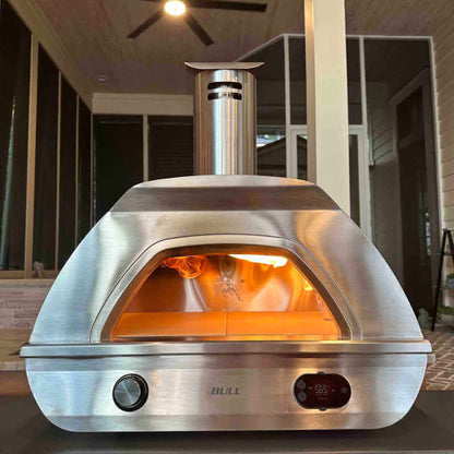 Bull Dual Fuel Pizza Oven in use – stainless steel outdoor pizza oven with gas burner on and digital temperature gauge showing 565°F.