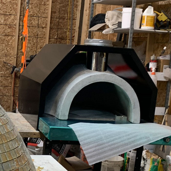 Di Napoli Series outdoor pizza oven with stainless steel hearth and custom enclosure installed in a luxury backyard kitchen.