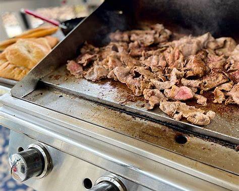 Bull commercial flat-top griddle cooking sliced meat on the stainless steel griddle surface.