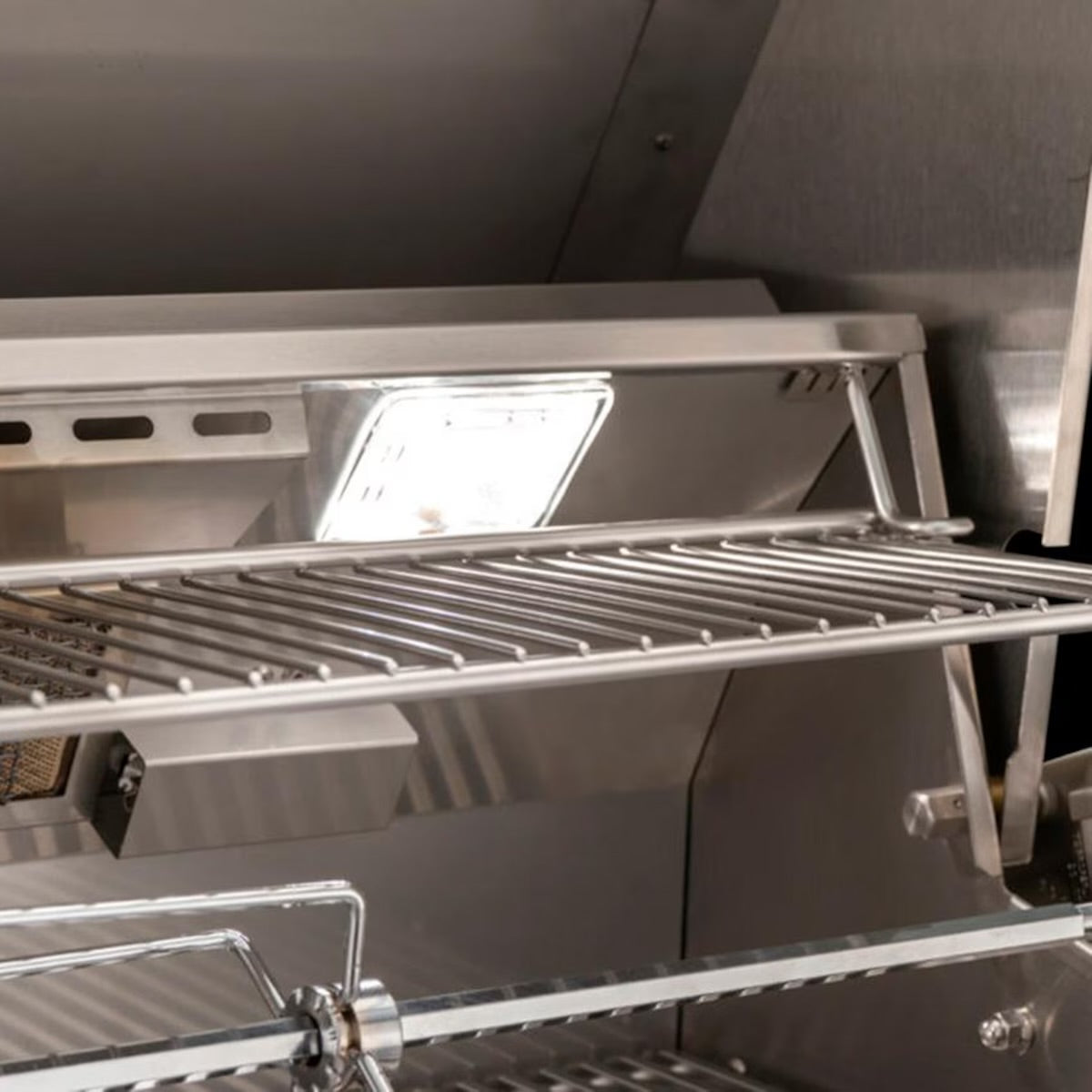 AOG American Outdoor Grill interior with stainless steel warming rack, built-in LED light, and rotisserie rod